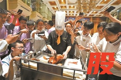 全聚德奥运村店的烤鸭厨师向师生们展示片烤鸭